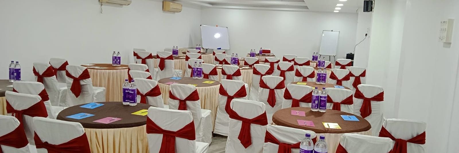 Round tables and chairs covered with cloth, and warm overhead lighting enhance and reside in the Emerald banquet hall of Mountview Resort.