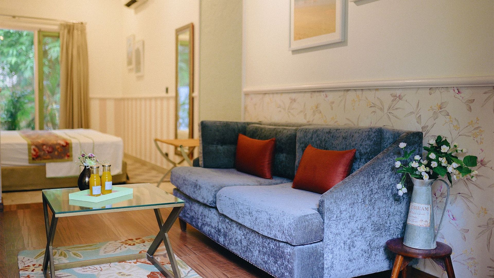 A sitting area at Karma Chalets with a grey sofa, red and green cushions, a coffee table, and artwork on the wall.