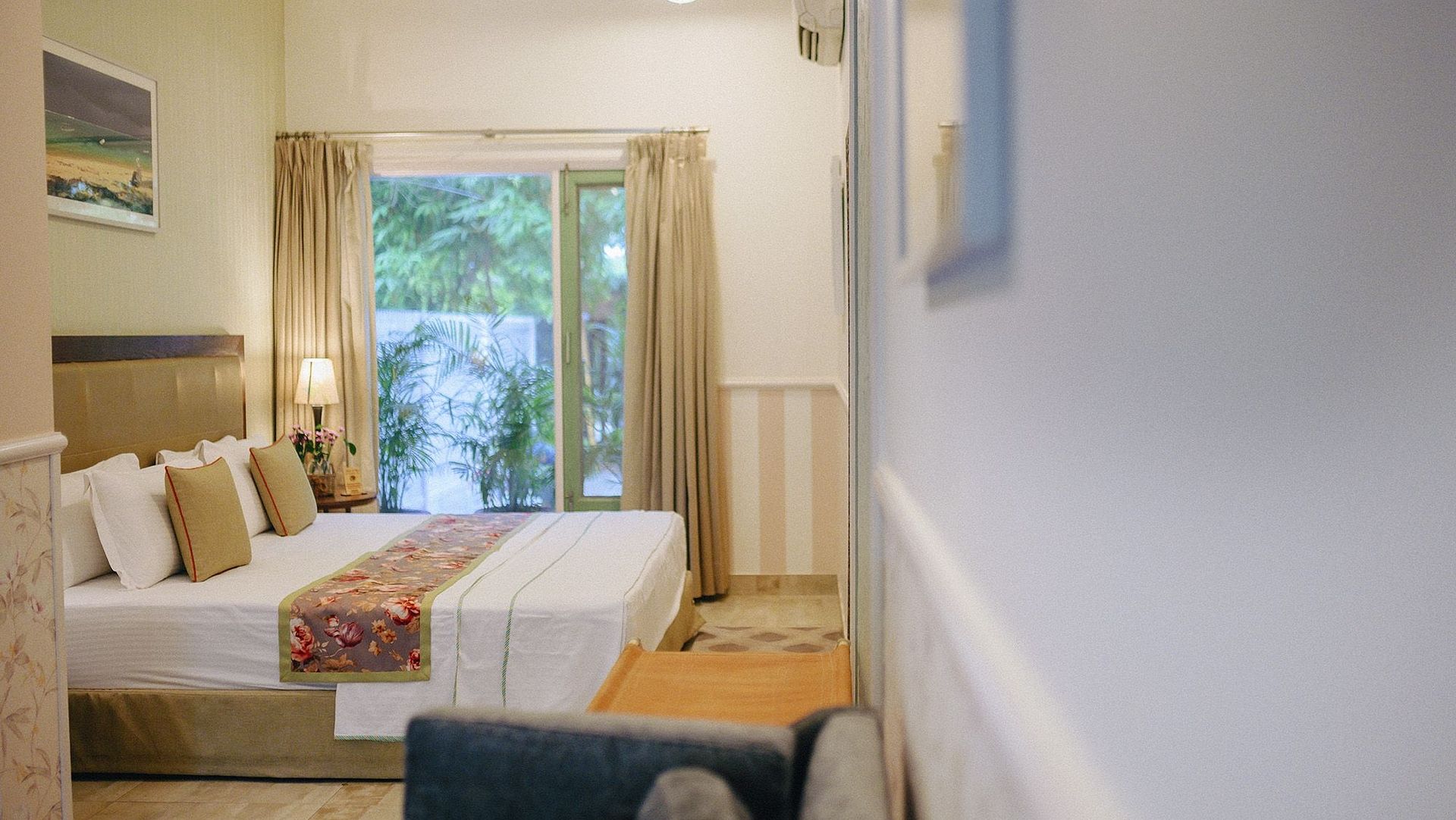 A double bed with white linens, cushions, and a window view at Karma Chalets.
