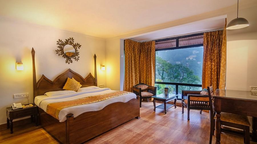 Spacious Deluxe Lake Facing Room with a cosy bed, two chairs and a table at Himalaya Hotel, Nainital