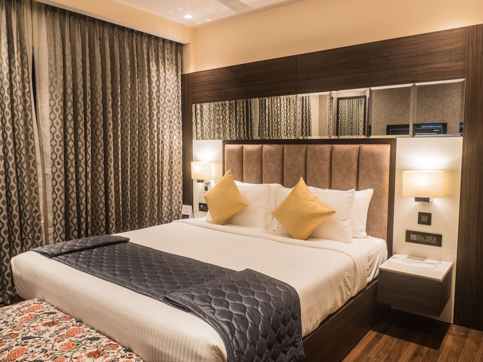 Comfortable king bed at Bergamont Hotels with side table and grey curtains.