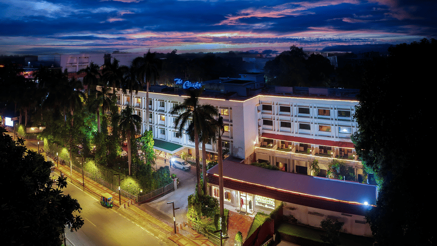An illuminated building The Clarks Varanasi, with several windows, trees, and sky in the backdrop.