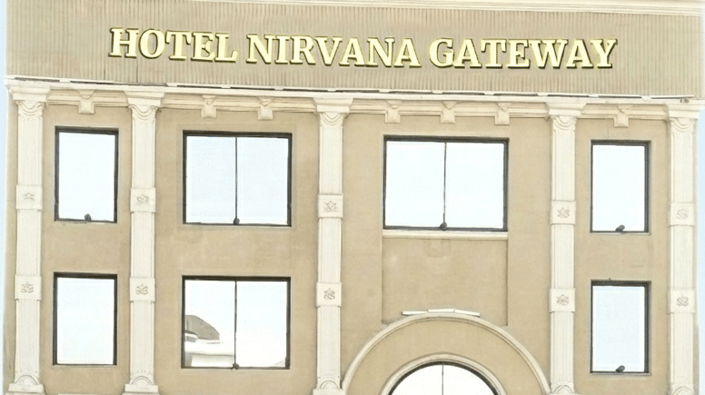 Facade of the multi-storey hotel, Nirvana Gateway, featuring block font name of the property, stairs leading up to the hotel, and windows.