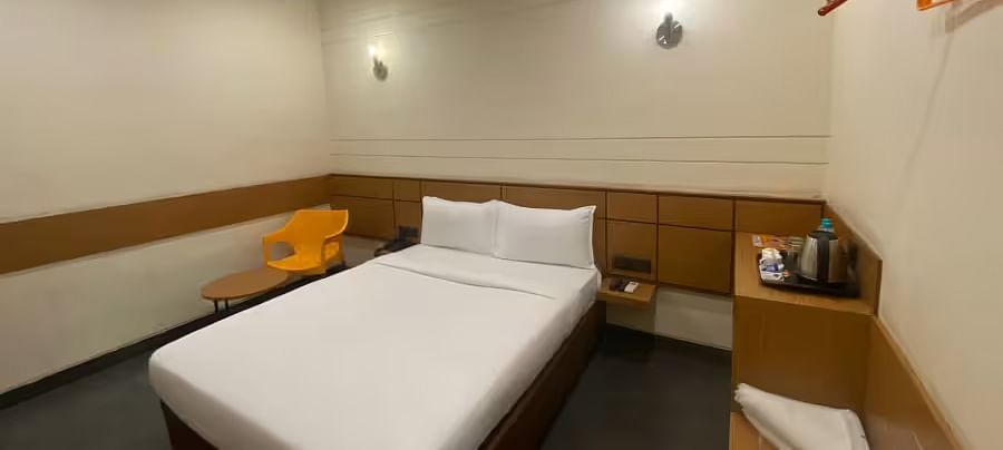 View of a hotel room with two single beds, a wooden table, and minimal decor - Max Hotel Prayagraj