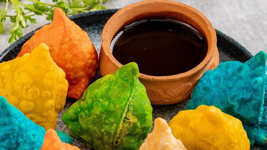 Traditional Indian snacks including samosas and sweets arranged on a serving plate with sauces.