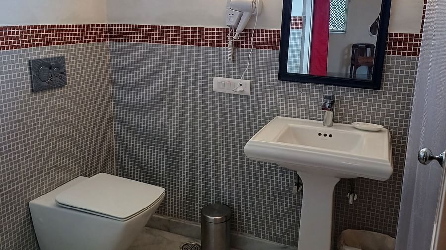 Compact bathroom with grey tiles, pedestal sink, and wall-mounted toilet at Neemrana Fort-Palace.