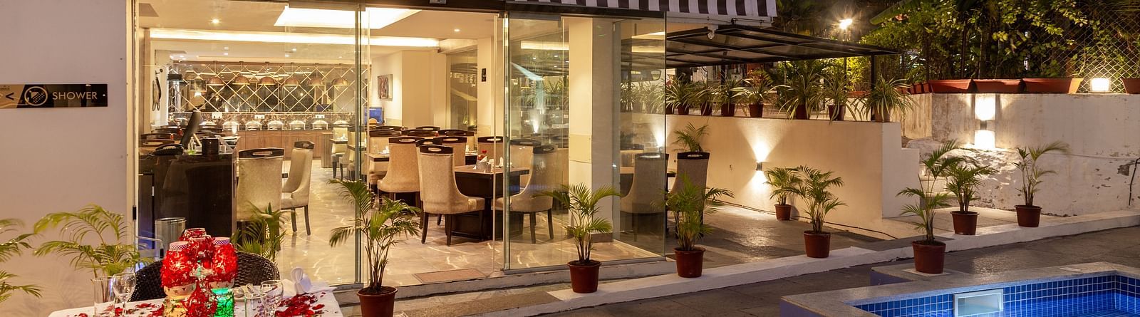 Image of poolside dining area with a table decorated with flowers at Calux Grand Baga.