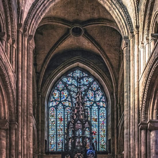 Interior view of a cathedral with the altar and a stained window behind it in view