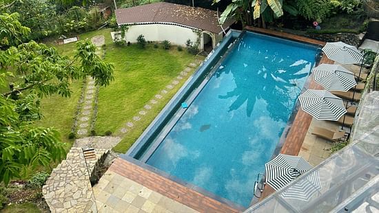 Tranquil swimming pool amidst a green, mountainous landscape. - VITS Select Kunjham, Gangtok