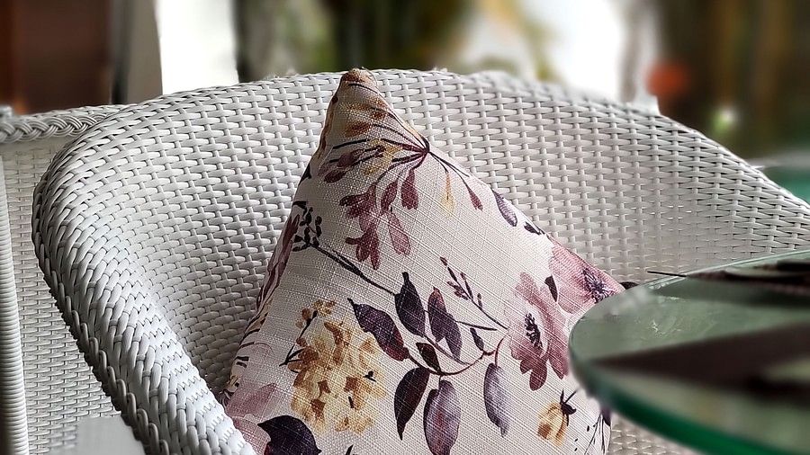 Close-up of a wicker chair with a floral cushion on a patio.