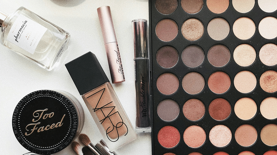 Beauty cosmetic products arranged on a table, featuring brushes and a vibrant color palette