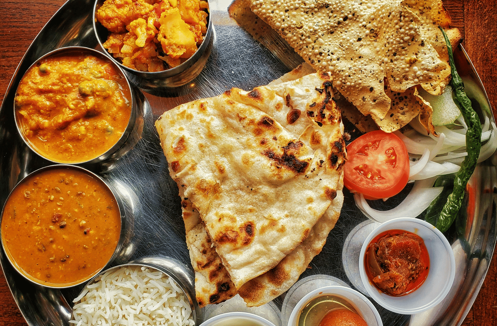 A neatly arranged plate with several Indian delicacies served.