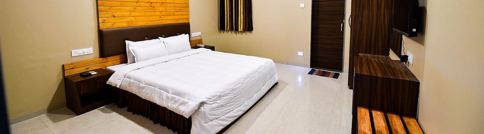 Overview of Deluxe Cottage at the Kanila Resort with a bed, bedside tables, wardrobe and a  ceiling fan.