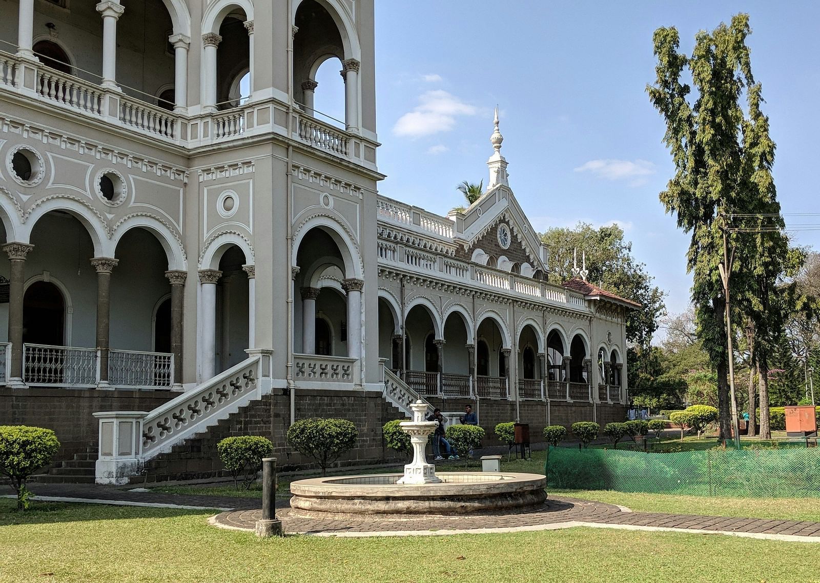 Facade view of Aga Khan Palace with a manicured garden in the foreground.