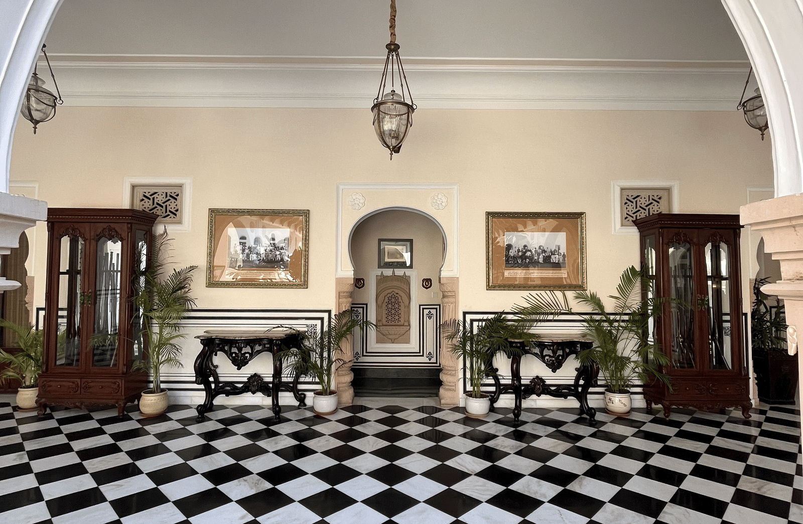 A grand hallway with a black and white tiled floor leading to an arched opening - Khas Bagh, Jaipur.