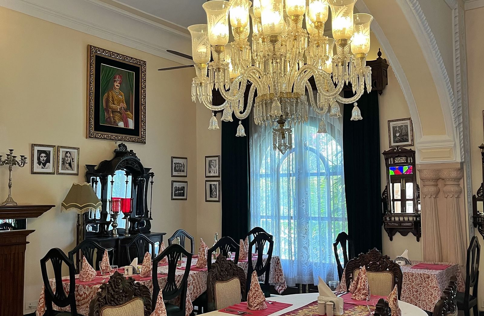 A well-appointed dining room featuring a large, illuminated chandelier above a dining table set with a runner and surrounded by chairs - Khas Bagh, Jaipur
