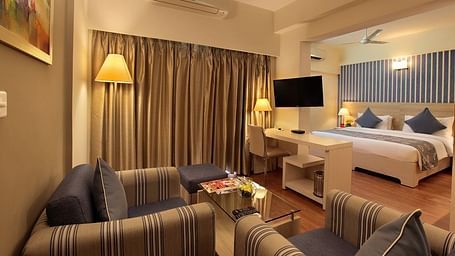 Deluxe room at Starlit Suites, Bangalore with a double bed and sofa seating