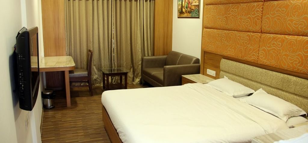 Well-lit hotel room with large bed, work desk, and TV