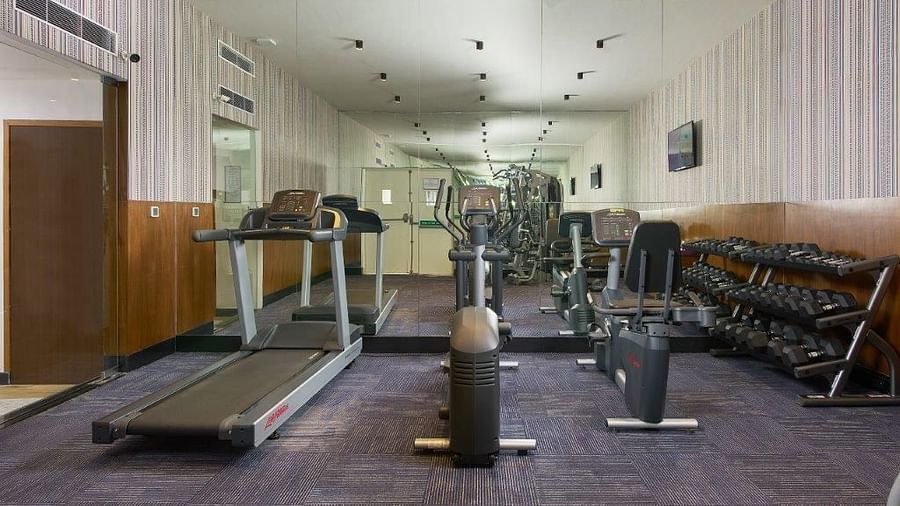 A wide-angle view of a gym with various exercise machines and equipment.