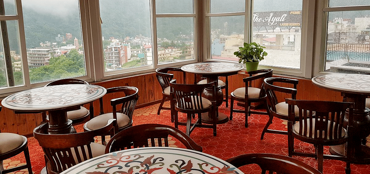 A close up shot of the restaurant with beautiful round dining table overlooking the city views from the window at Regenta Inn DLS.