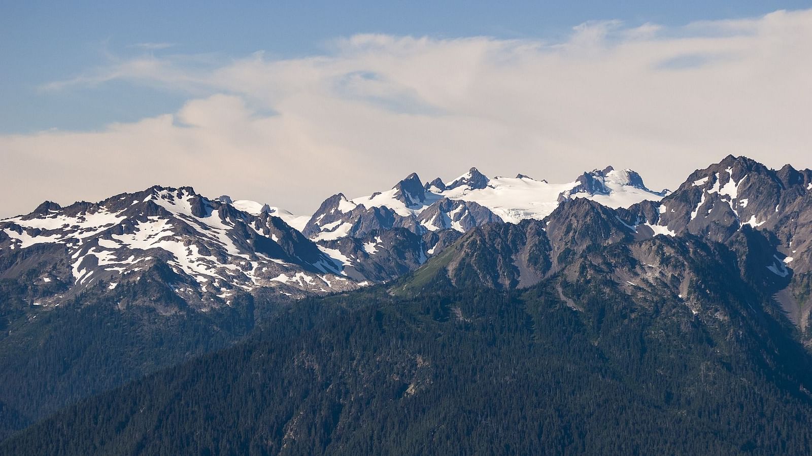 A panoramic view of a mountain landscape with clouds and colorful flags, showcasing a beautiful valley.