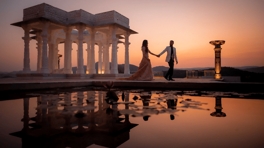 Couple holding hands at sunset near elegant marble pavilion at Fateh Vilas Collection Udaipur