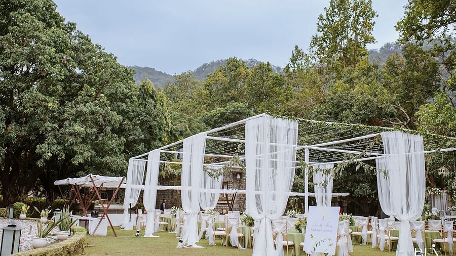 Elegant wedding setup with white curtains surrounded by lush greenery in a beautiful outdoor venue