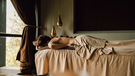 Woman lying on a massage table with hot stones on her back.