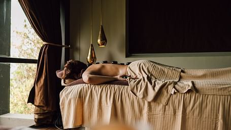 Woman lying on a massage table with hot stones on her back.