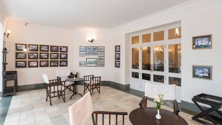 The waiting space adorned with images on the wall at The Claridges Nabha Residence in Mussoorie, equipped with chairs and tables.