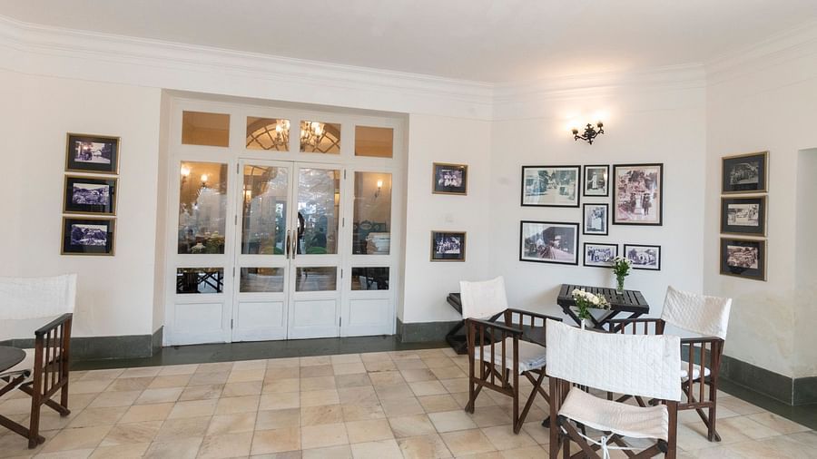 The waiting area in The Claridges Nabha Residence, Mussoorie, is furnished with chairs, tables, wall paintings, and various decorative items.