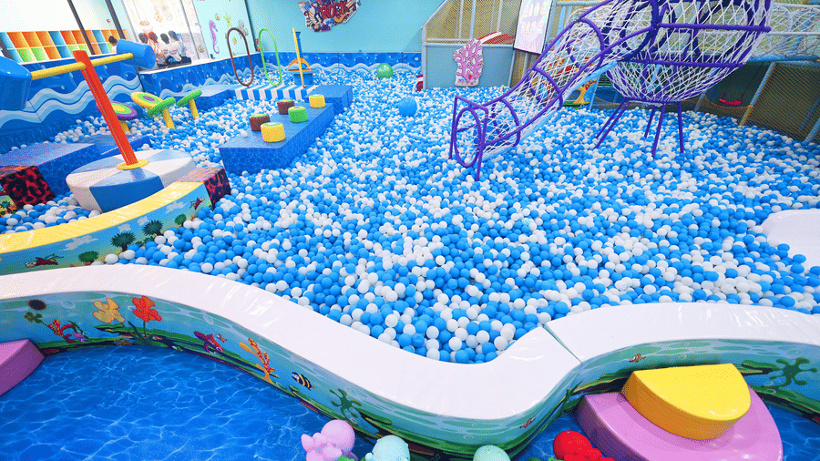 A large ball pit at Tic Tac Tot is filled with thousands of play balls and features a net tunnel for climbing.