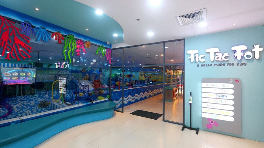 The main glass door entrance of Tic Tac Tot showcases the logo and a clear view of the indoor play area.