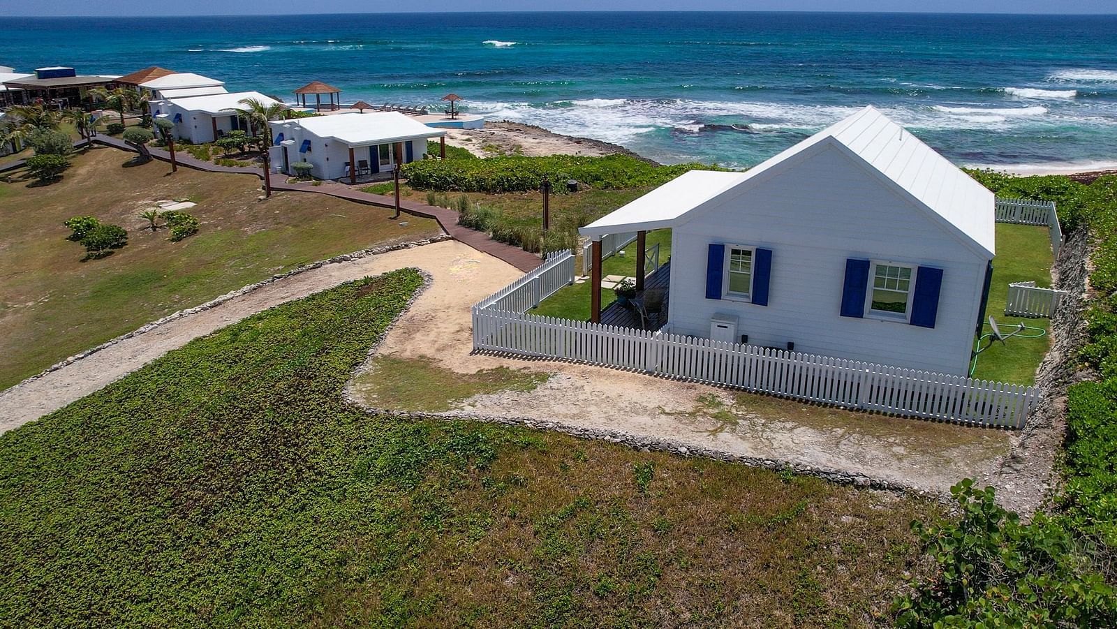 Hill Top Cottage at Abaco Inn shown from the front, set against the sea in the background.
