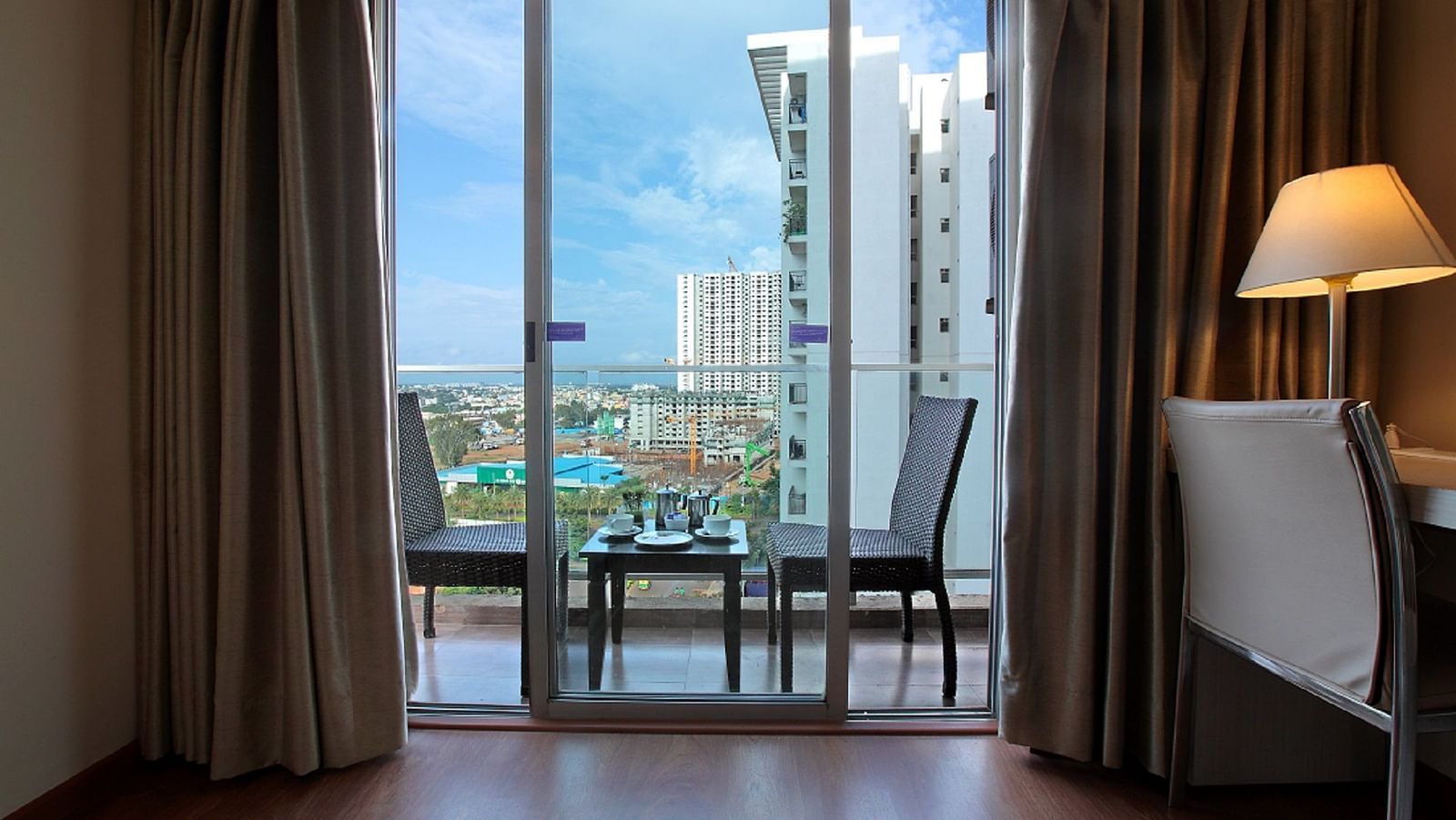 Premium Studio at Starlit Suites, Bangalore with seating arrangement in the balcony with the cityscape in the backdrop