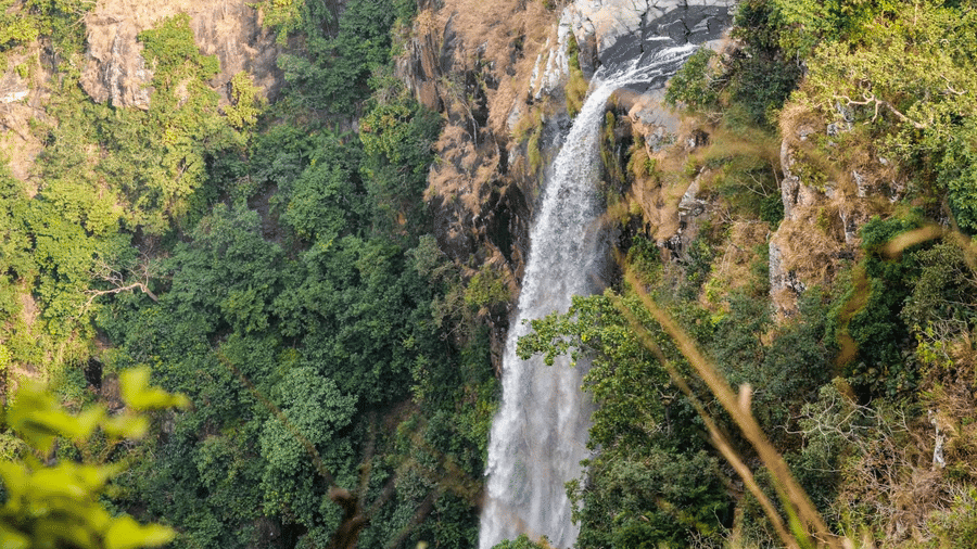 Joronda waterfall cascading down a steep cliff surrounded by thick forest vegetation near Khairi Resorts.