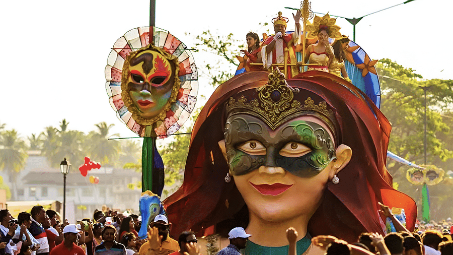 A large, colorful effigy, part of a religious procession or festival in Goa, carried through a crowd.