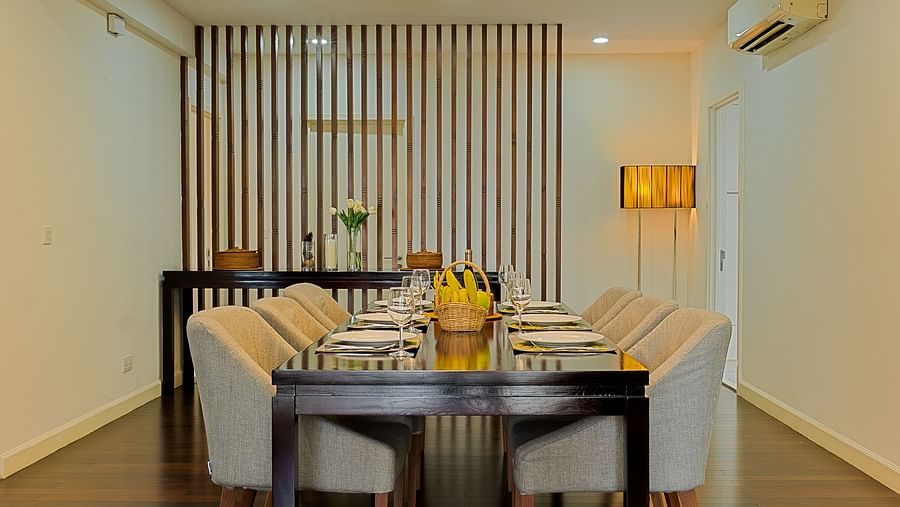 A dining area with a wooden table, chairs, and a chandelier overhead | Penthouse | Central Mansions, Phnom Penh