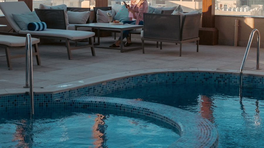 Poolside seating with patio and city views at La Maison Hotel, Doha.