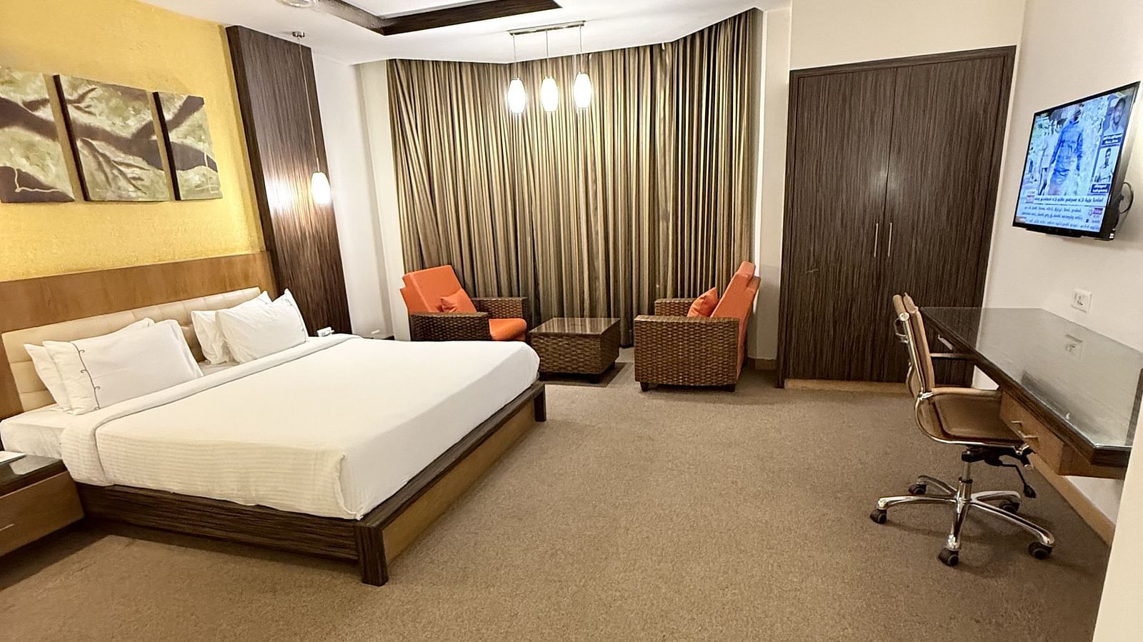 A spacious room with a large bed, cushioned seating beside the window with curtains, and a TV with a writing desk to the side | Cenneys Gateway