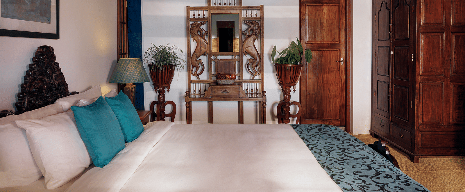 A shot taken from the side of the bed, with a wooden wardrobe and dress in the background - BluSalzz Villas - Muhamma Resort, Alleppey