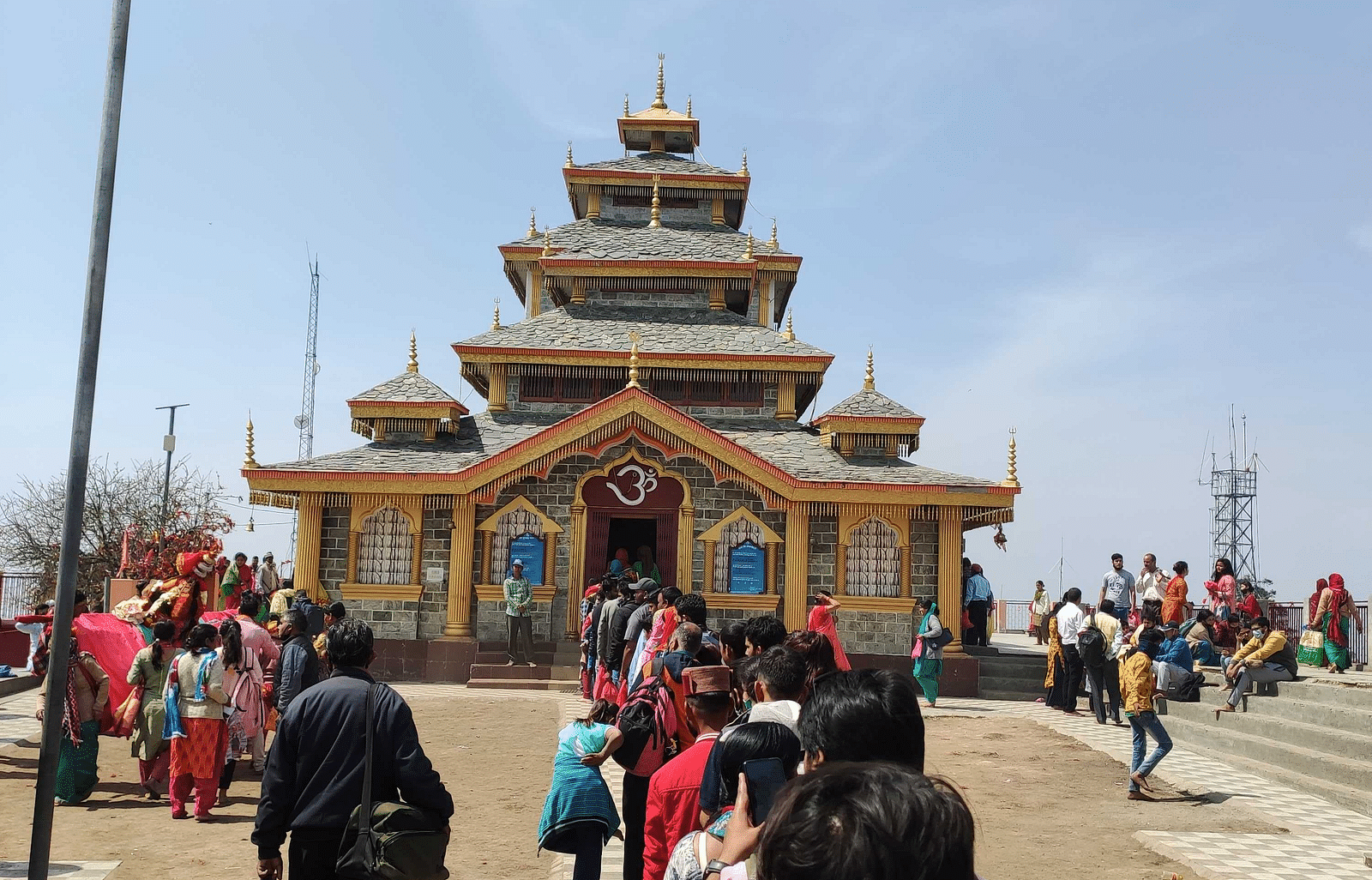 An image of a monastry style temple and outside the temple there is a queue of devotees