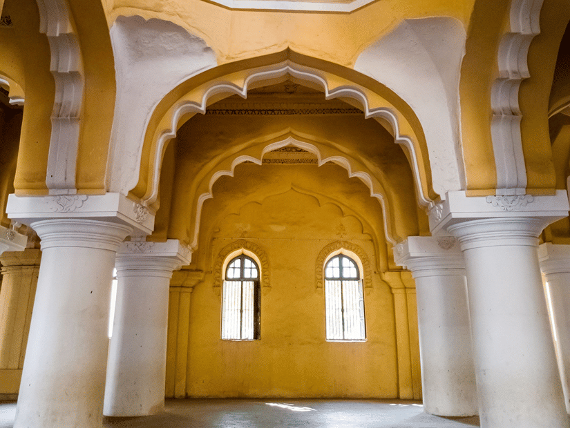 Interior view of grand yellow and white arches leading up to a domed ceiling supported by pillars.