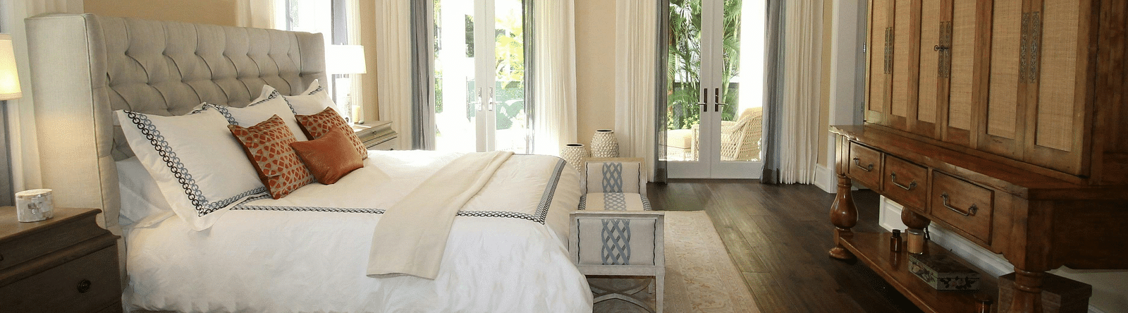 Spacious bedroom with a vaulted ceiling, chandelier, and large windows.