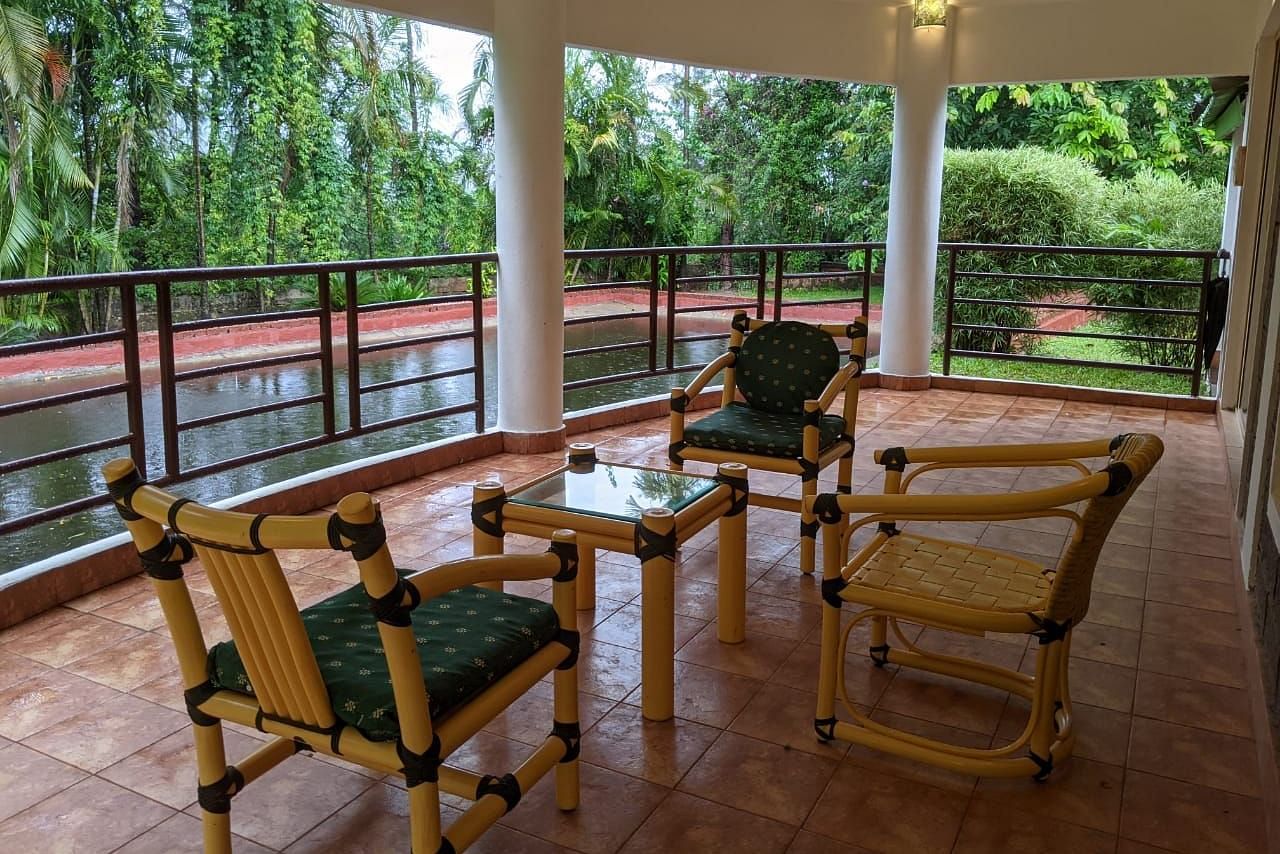 Outdoor seating area on a covered balcony with a scenic forest view at The Conservancy Bungalow.