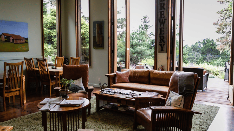 Bright and open lounge space with wooden chairs, a fireplace, and large glass doors overlooking nature - Brewery Gulch Inn & Spa