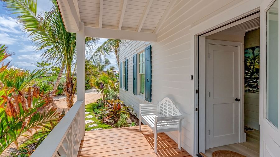 Covered porch with tropical plants and an entrance to the building | Abaco Inn