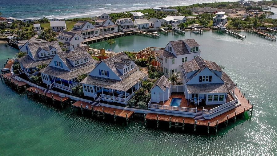 Drone view of villas and bungalows built over water with wooden decks, forming a semi-circle above a calm bay | Abaco Inn