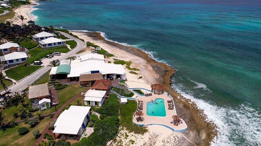 Coastal resort captured from above, featuring a swimming pool, beachside villas, and turquoise ocean waves | Abaco Inn