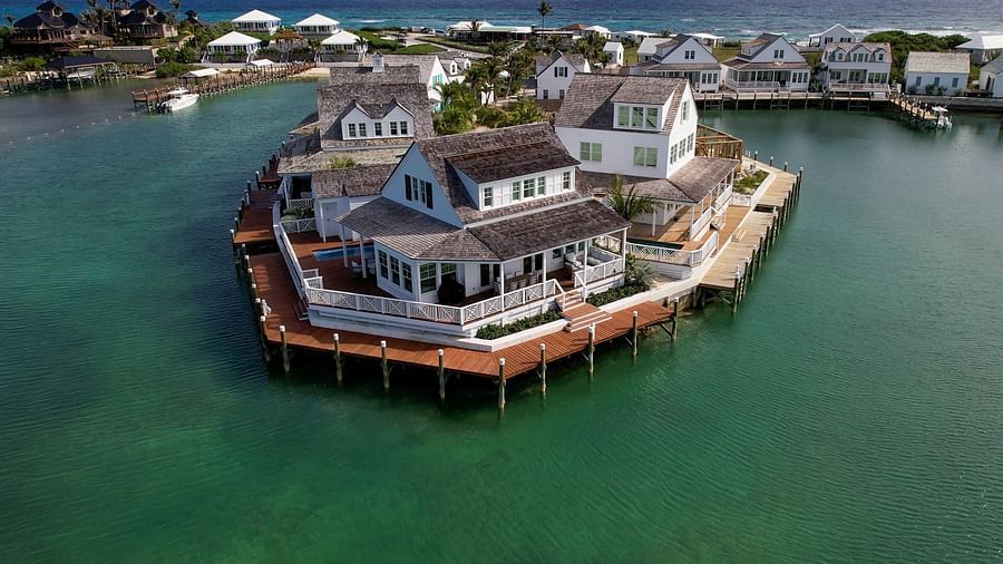 Round building on stilts in the water, connected to shore by a bridge, seen from above in a clear aerial shot | Abaco Inn